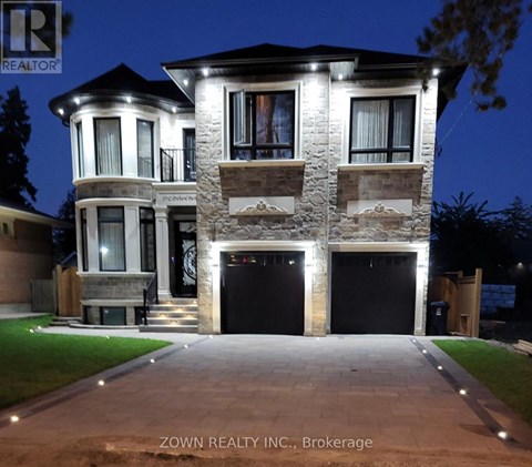 A house with a stone facade and a large front yard is illuminated at night.