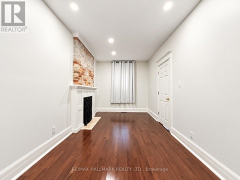 A spacious room with a fireplace and wooden floors.