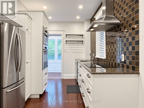 A kitchen with white cabinets and a stainless steel refrigerator.