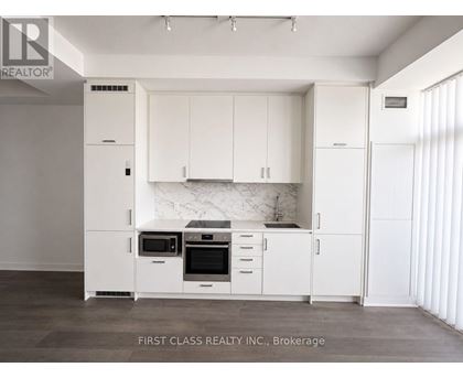 A kitchen with white cabinets and appliances in a brokerage.