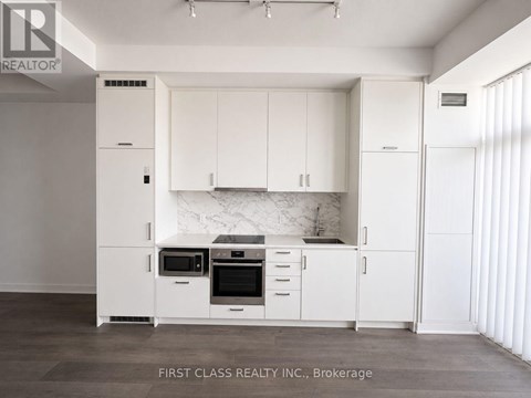 A kitchen with white cabinets and appliances in a brokerage.