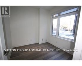 A room with a window and a sign that says Sutton Group-Admiral Realty Inc., Brokerage.