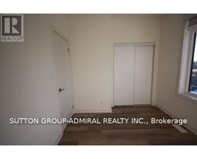 A room with a door and a window with Sutton Group-Admiral Realty Inc., Brokerage written on the wall.