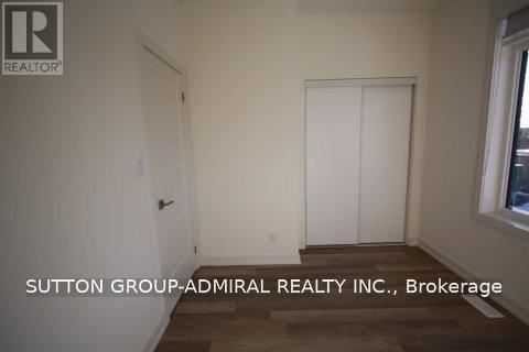 A room with a door and a window with Sutton Group-Admiral Realty Inc., Brokerage written on the wall.