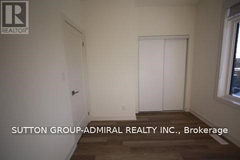 A room with a door and a window with Sutton Group-Admiral Realty Inc., Brokerage written on the wall.