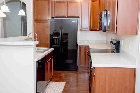A black refrigerator in a kitchen with wooden cabinets.