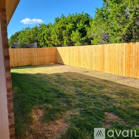 A backyard with a wooden fence and green grass.