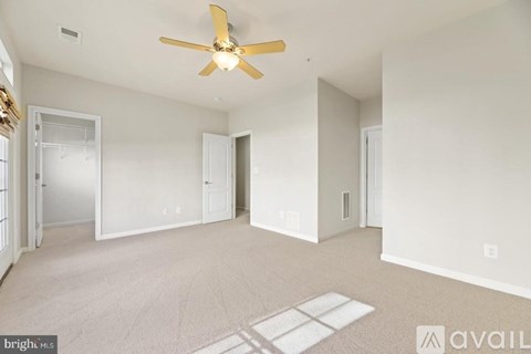 A spacious room with a ceiling fan and carpeted floor.