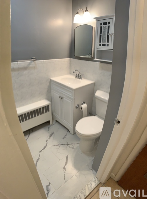 A bathroom with a toilet, sink, and mirror.