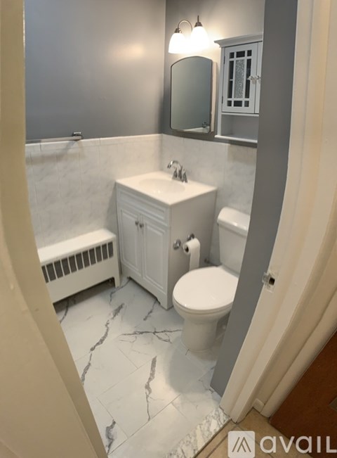 A bathroom with a toilet, sink, and mirror.