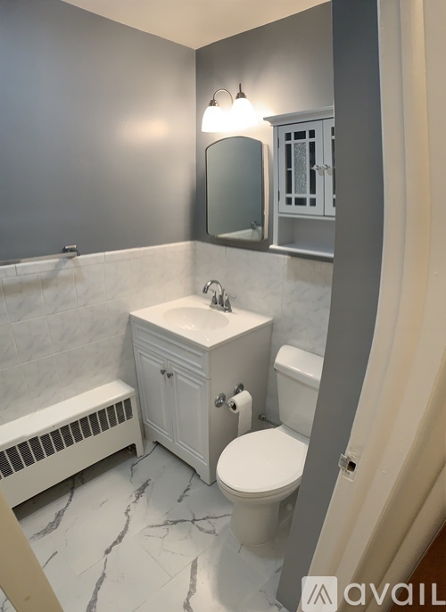 A bathroom with a toilet, sink, and mirror.