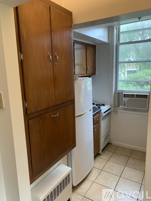 A kitchen with a white refrigerator and wooden cabinets.