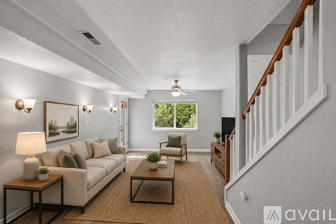 A living room with a white couch, a coffee table, and a ceiling fan.