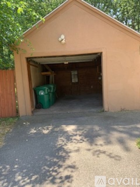 A small building with a green trash can in front of it.