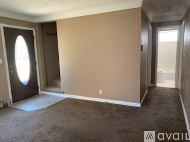 A room with a carpeted floor and a door with a window cut out in it.