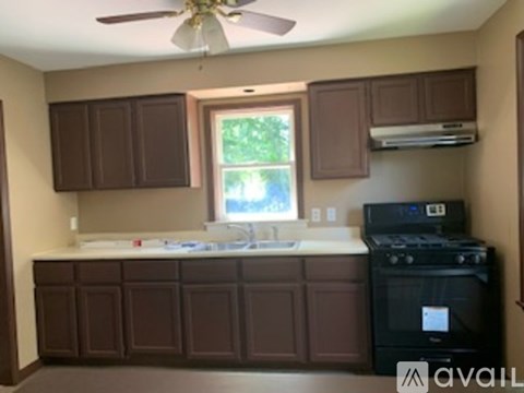 A kitchen with brown cabinets and a black stove.