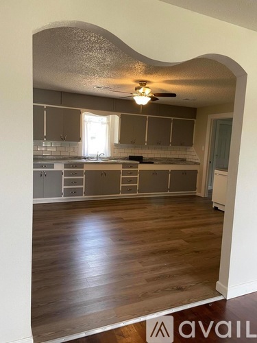 A kitchen with wooden floors and a ceiling fan.