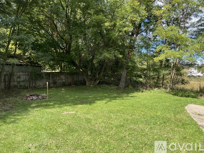 A backyard with a grassy area, trees, and a wooden fence.