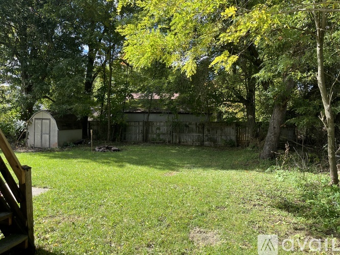 A backyard with a wooden deck and a tree with yellow leaves.