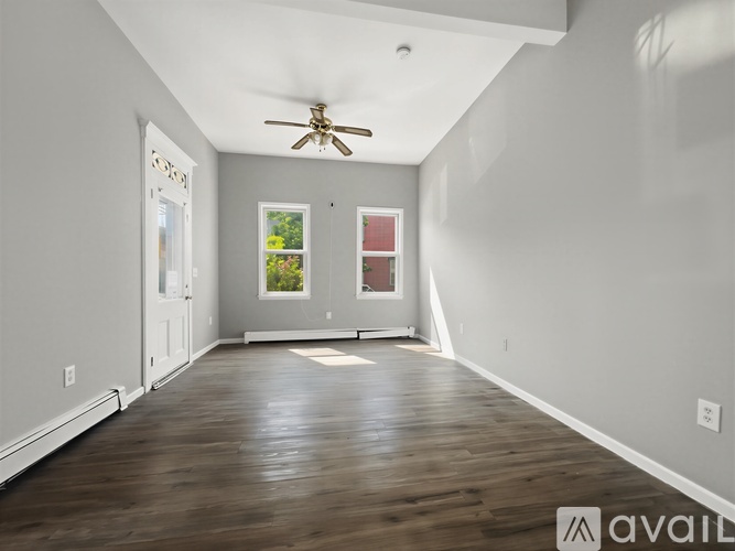 A spacious room with a ceiling fan and wooden flooring.