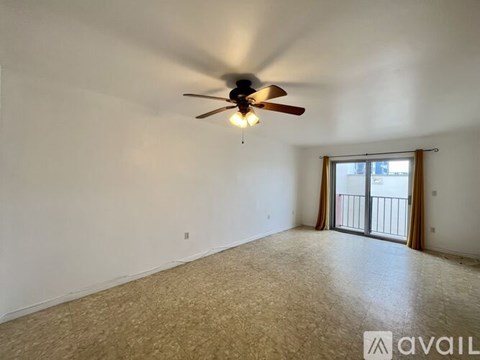 A room with a ceiling fan and a sliding glass door leading to a balcony.