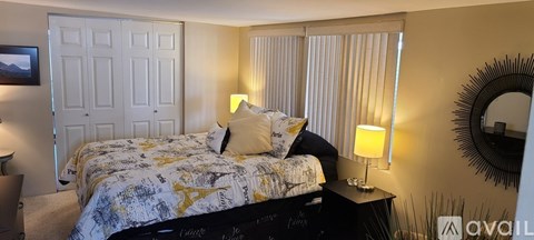 A bedroom with a bed, nightstand, and a mirror on the wall.