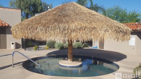 A pool with a thatched roof umbrella over it.