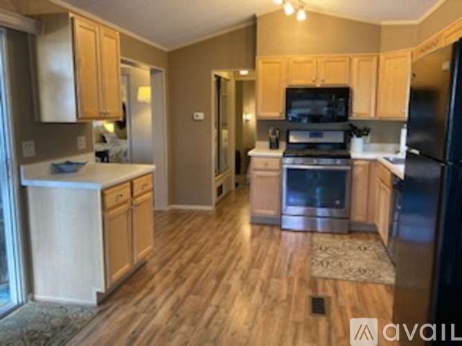 A kitchen with wooden cabinets and a black refrigerator.