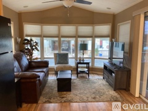 A living room with a brown leather couch, a coffee table, and a television.