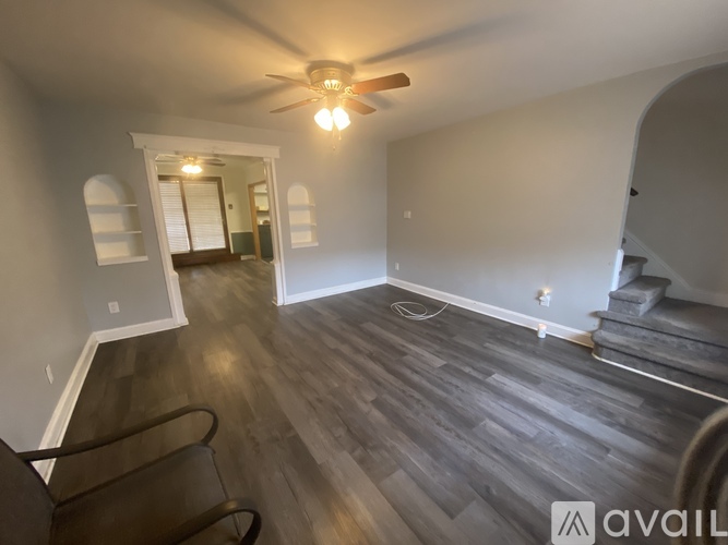 A room with a ceiling fan and wooden flooring.