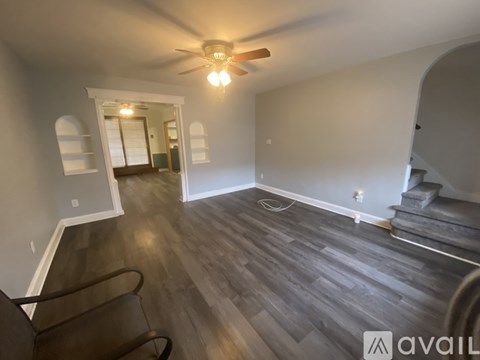 A room with a ceiling fan and wooden flooring.