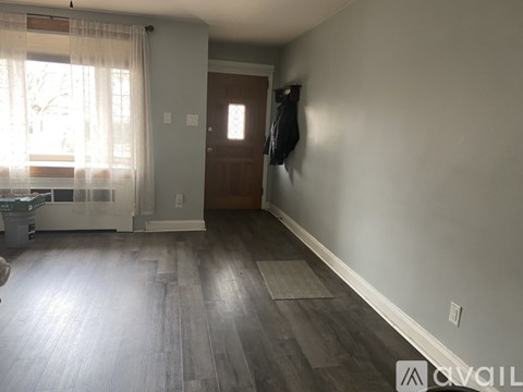A room with a wooden floor and a window with curtains.