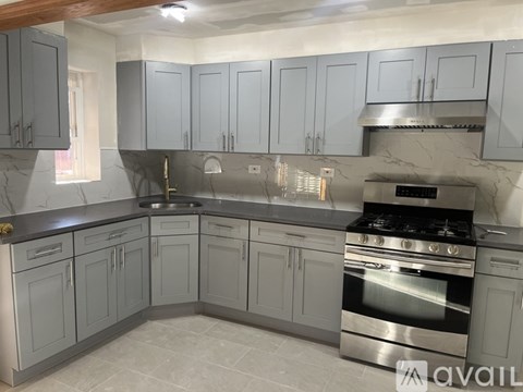 A kitchen with grey cabinets and a stainless steel oven.