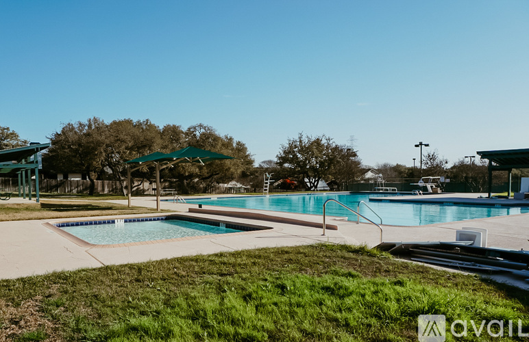 A swimming pool surrounded by a grassy area and trees.