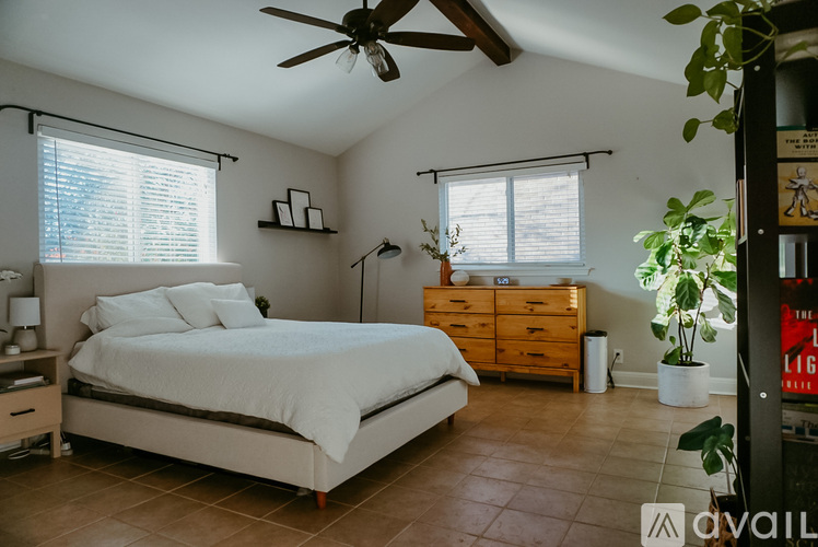A bedroom with a bed, dresser, and ceiling fan.