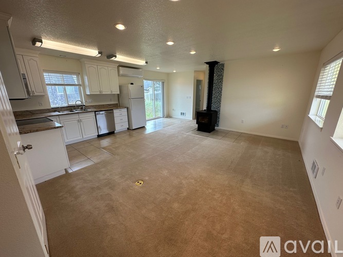 A spacious living room with a kitchen area in the background.