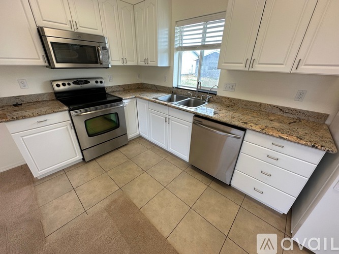A kitchen with white cabinets and a granite countertop.