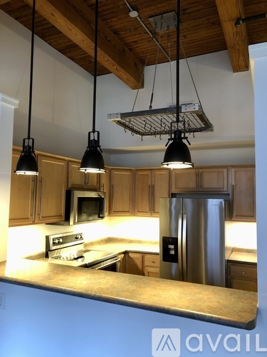 A kitchen with wooden cabinets and a stainless steel refrigerator.