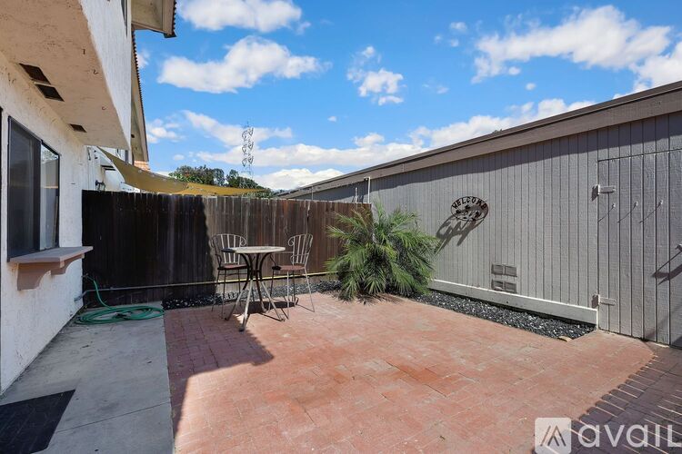 A patio with a table and chairs is surrounded by a wooden fence.