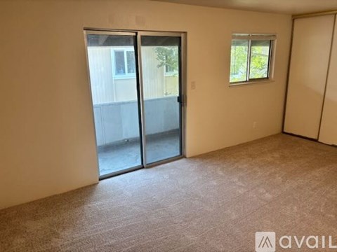 A room with a carpeted floor, a sliding glass door, and a small window.
