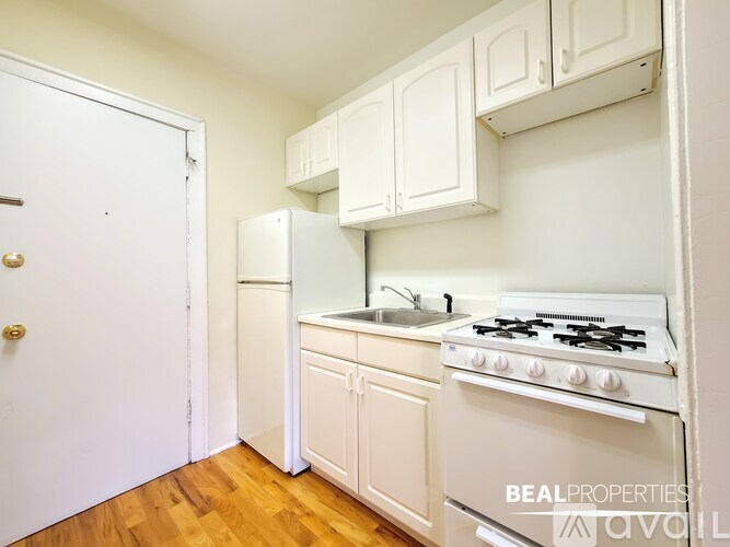 A white kitchen with a stove, sink, and cabinets.