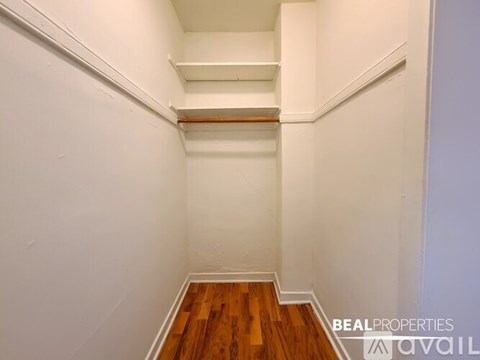 A white hallway with wooden floors and a white wall.