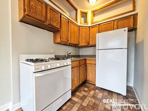 A white stove and refrigerator in a kitchen with wooden cabinets.