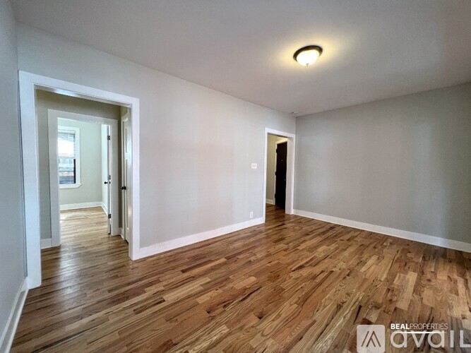 A room with wooden flooring and white walls, with a door on the right side.