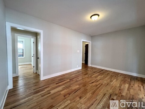 A room with wooden flooring and white walls, with a door on the right side.