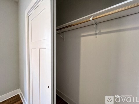 A white door is on the left and a white closet with a rod on the right.