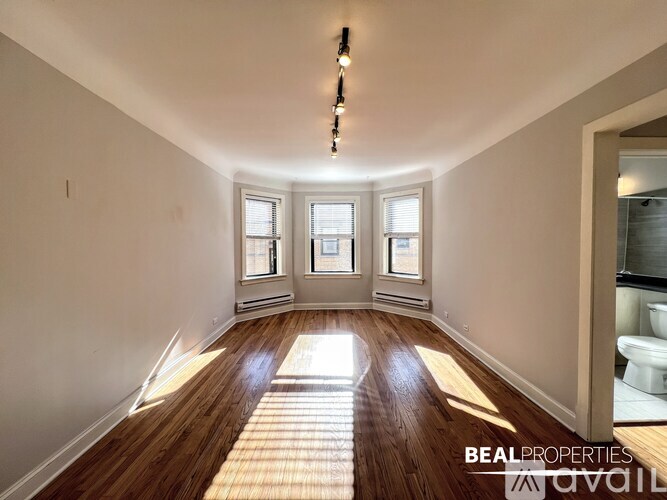 A sunlit room with wooden floors and white walls.