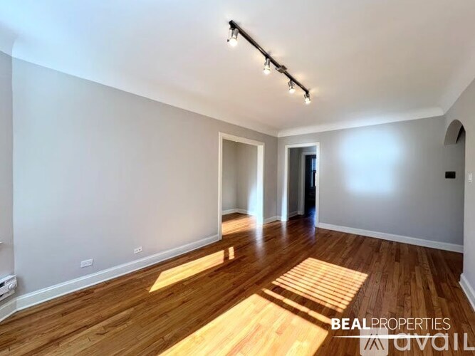 A spacious room with wooden flooring and white walls.