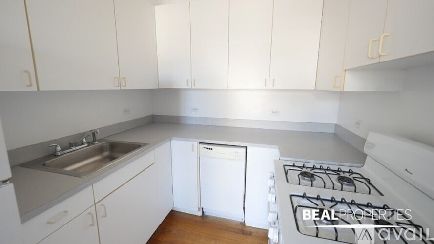 A kitchen with white cabinets and a white stove top oven.