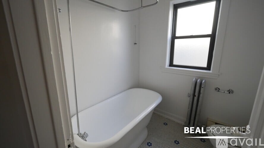 A white bathroom with a tub, toilet, and window.